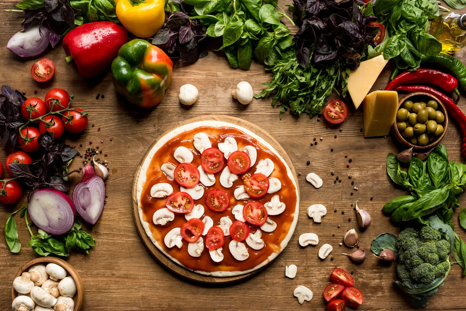 Pizza being prepared among fresh ingredients